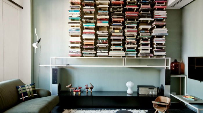 A living room with many shelves on the wall filled with books in a modern Turin home.