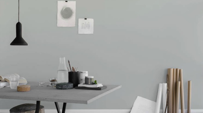 An artist's workspace demonstrating the grey trend with soft grey walls, a grey work table with rolled up paper leaning against the wall.