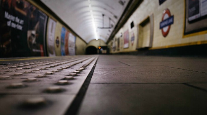 A close up of the pavement of a tube stop with the tube tunnel in the background in the London Underground series by Mark Cornick.