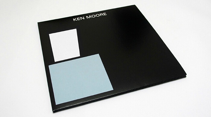 A minimalist record sleeve by Jelle Martens in black with white and blue abstract sqaures on the front with the artist name 'Ken Moore' in white letters at the top.