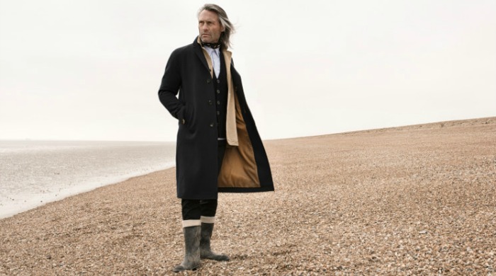 A man wearing Private White V.C clothing on a beach.