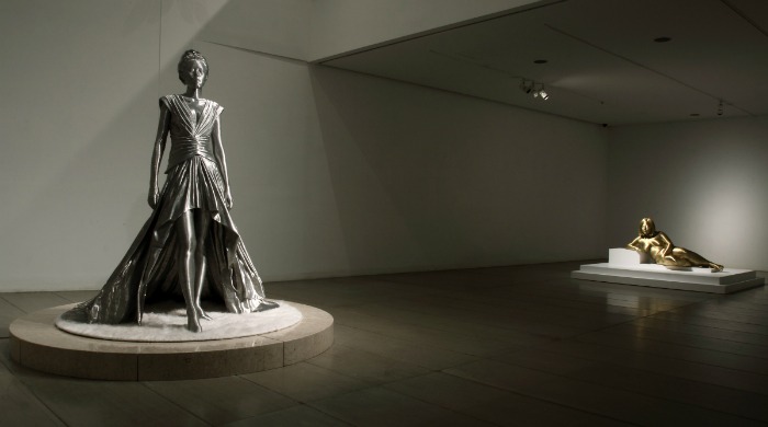 A silver statue of a woman in a long dress by Seung Mo Park.