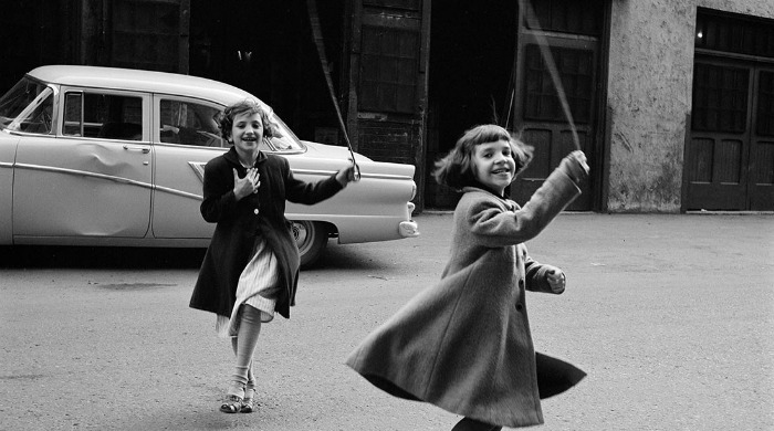 A street photograph of two girls playing by Vivian Maier.
