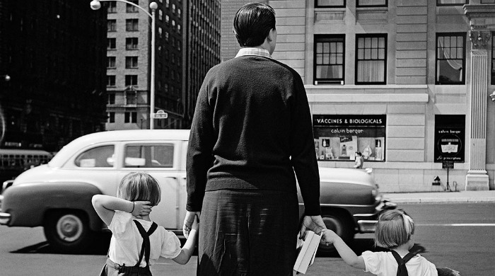 A street photograph of a family crossing the street by Vivian Maier.