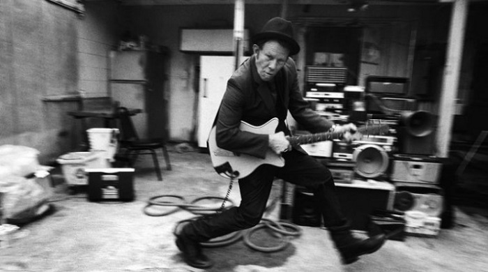 Tom Waits playing guitar photographed by Danny Clinch.