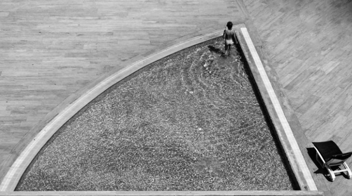 A figure standing in a shallow triangular pool by Kjetil Karlsen.