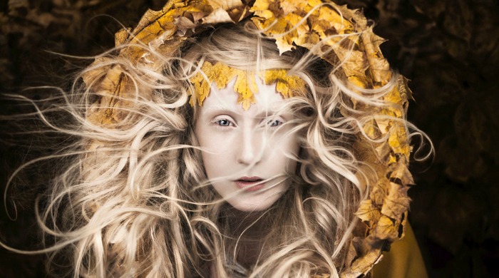 A girl wearing a hood of yellow leaves from 'Wonderland' by Kirsty Mitchell.