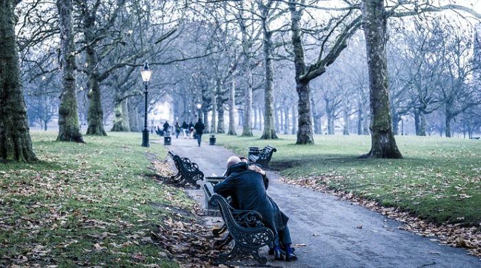 A photo of two people hugging on a park bench by Aaron Hargreaves.