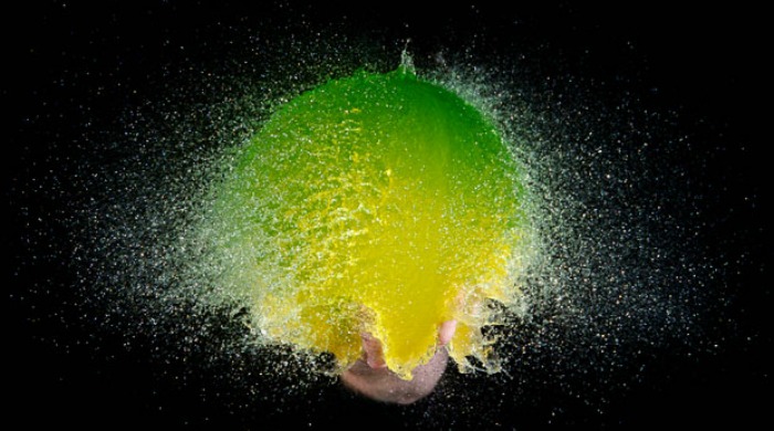 A green and yellow water balloon bursting by Edward Horsford.