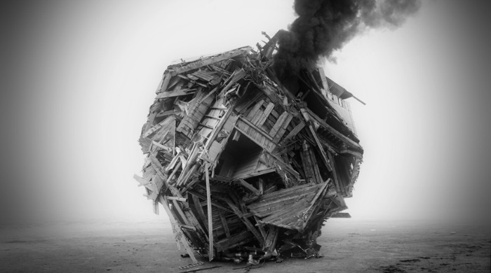 A smoking ball of wooden planks on the beach in black and white by Jim Kazanjian.
