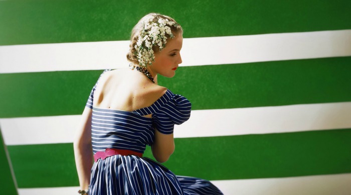 A model in a blue dress against a green and white striped backdrop in the V&A Horst Exhibition.
