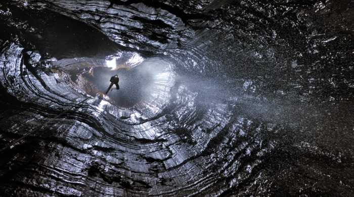 A caver descending into a cave by Robbie Shone.