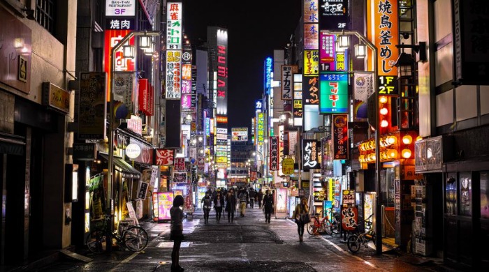A street in Tokyo lit up by neon signs by Noisy Paradise.