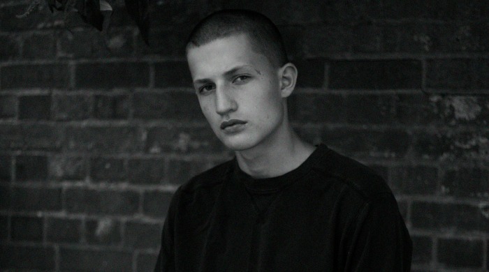 A portrait of a male model with a shaved head in black and white by Sarah Louise Stedeford.
