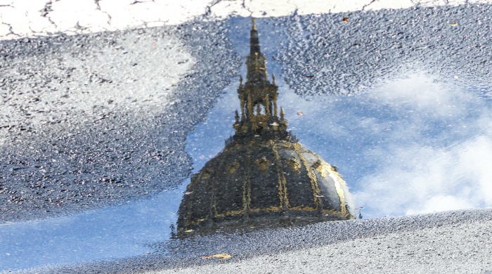 The dome and spire of San Francisco city hall reflected in a puddle by Angela May Chen.
