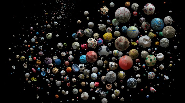A group of old footballs from a varity of different countries seemingly floating in a black space from 'Penalty' by Mandy Barker.