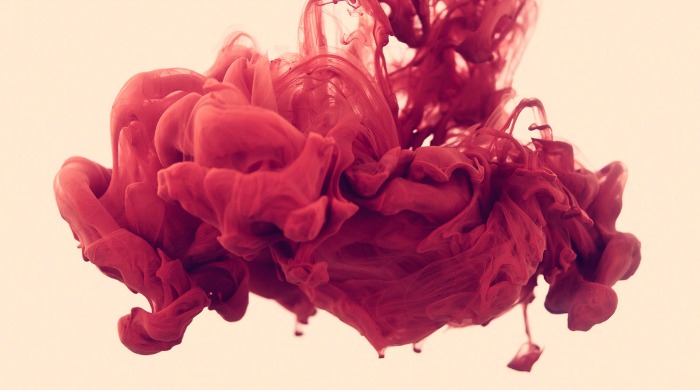 A plume of ink in red in water by Alberto Seveso.