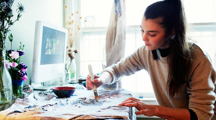 Audrey Louise Reynolds painting at a desk.