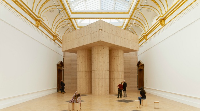 A wooden structure in a large exhibition space at the Royal Academy of the Arts.