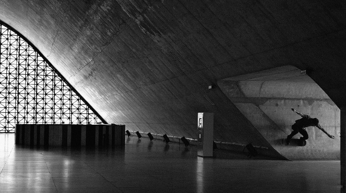 Fabiano Rodrigues skateboarding inside a large concrete space.