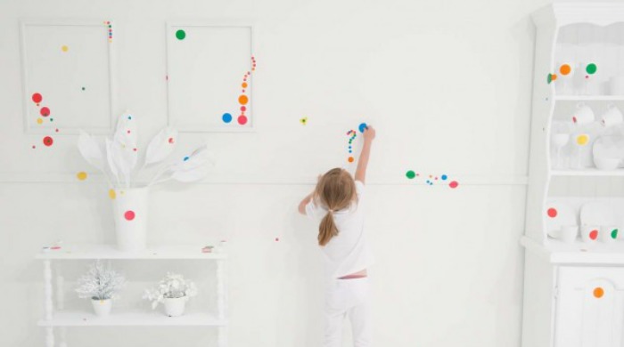 A child placing a sticker on the wall of the Obliteration Room by Yayoi Kusama.