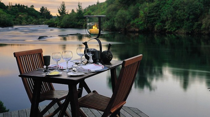 An outdoor dining table next to the lake at Huka Lodge, New Zealand.