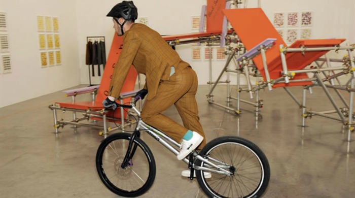 A male model wearing a suit and riding a bike for the London Collections Men Paul Smith SS16 collection.