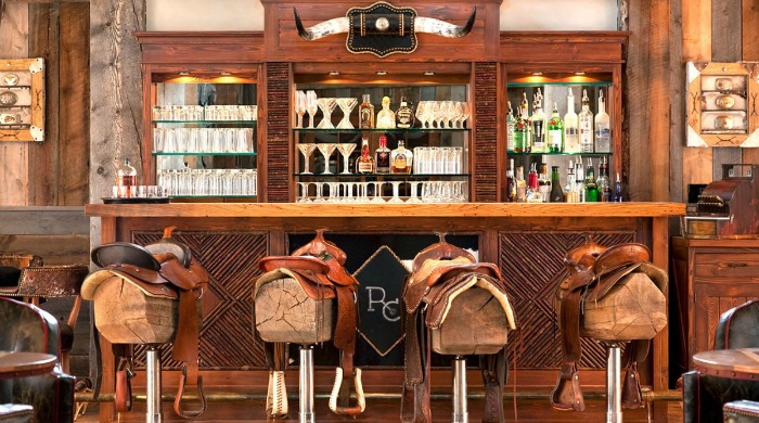 A bar with saddles over the bar stools at The Ranch at Rock Creek.