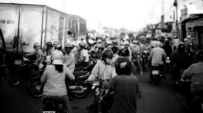A crowd of people on scooters wearing dust masks in Vietnam by David Do.